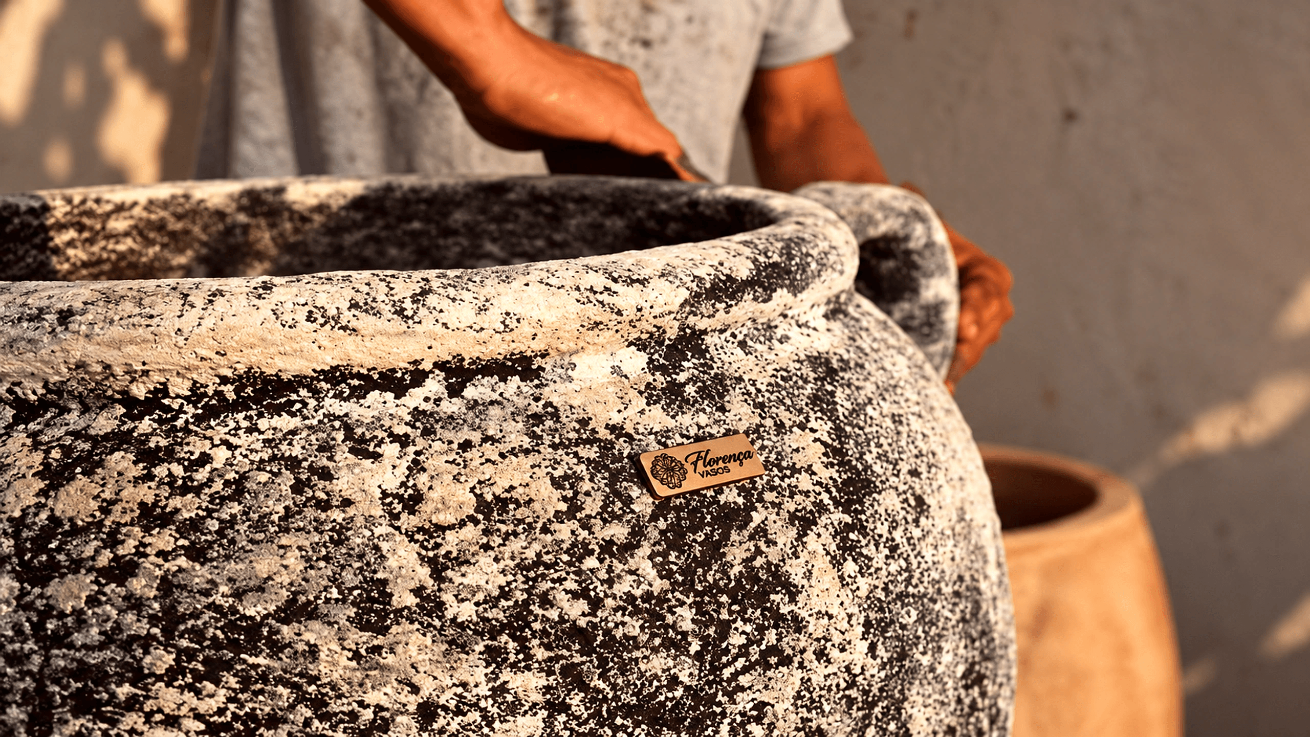 Artesão da Florença lixando à mão um vaso de concreto com textura granito